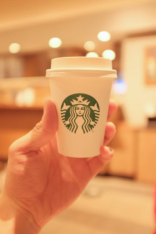 a person holds up a starbucks cup in their hand