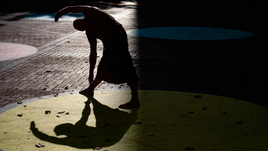 the person standing in the sun is doing an upside down trick