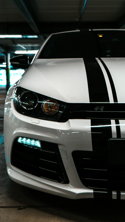 a white car with black stripes parked inside of a building