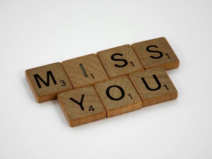 a wooden scrabble saying miss you and miss you