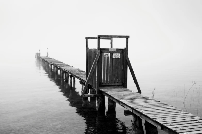 a wooden dock extending into the water in a foggy day