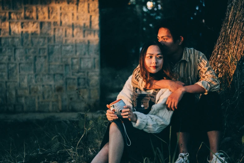 a young couple is sitting under a tree