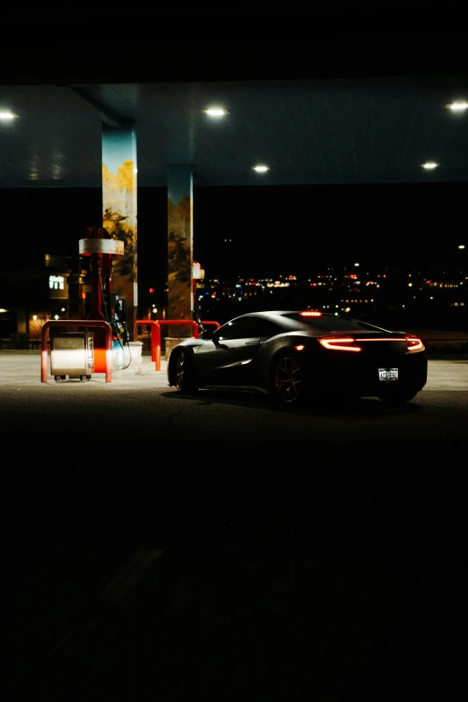 the car is at the gas pump by night