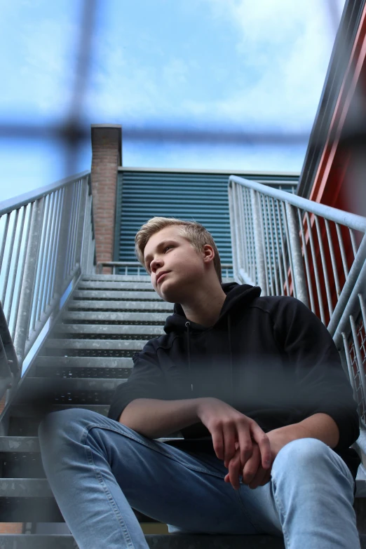 a young man sits at the bottom of stairs