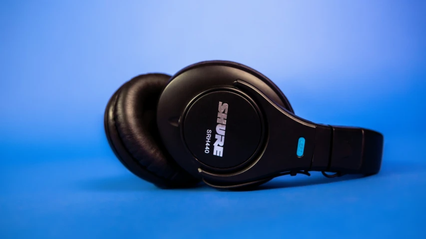 a pair of black headphones are lying on a blue background