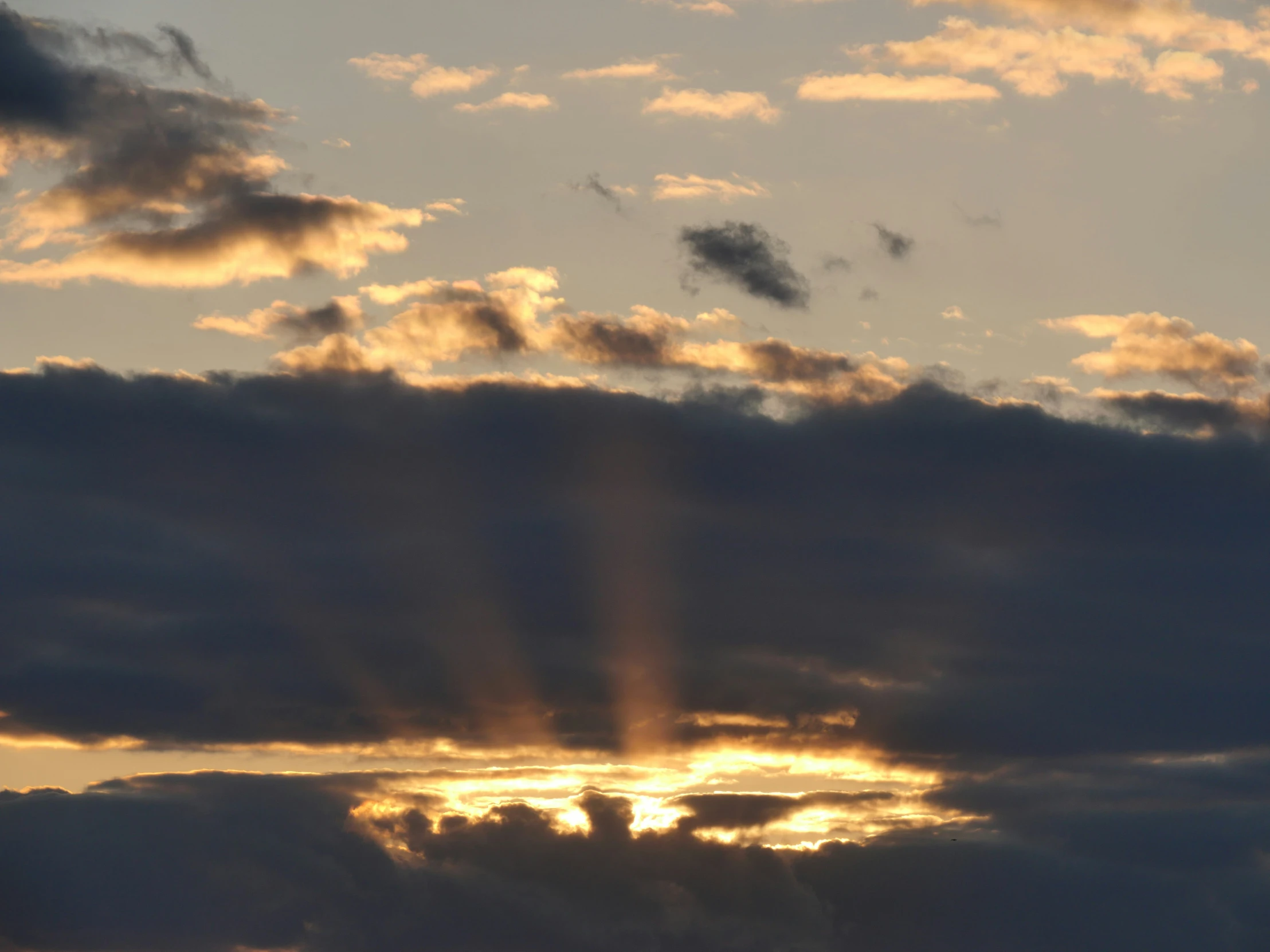 the sun rays shine in front of a cloudy sky