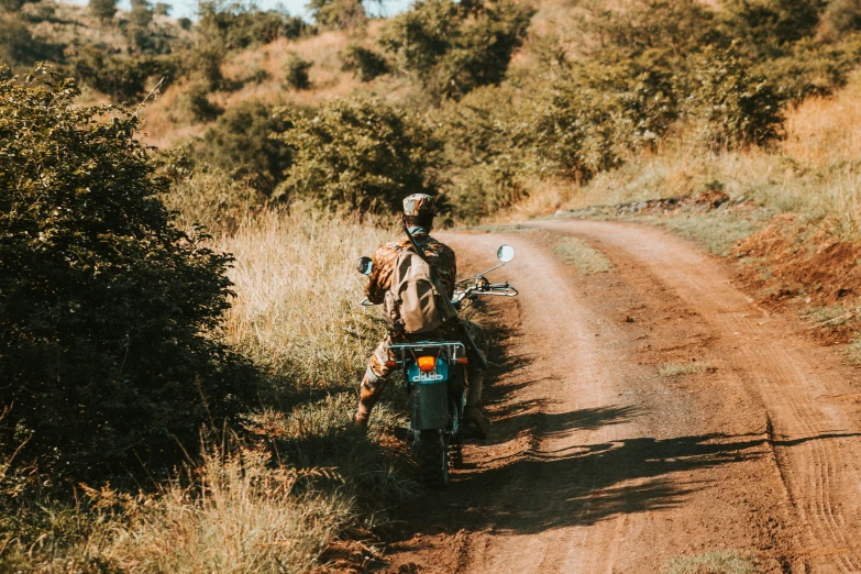 a person sitting on a motorcycle in the middle of a dirt road