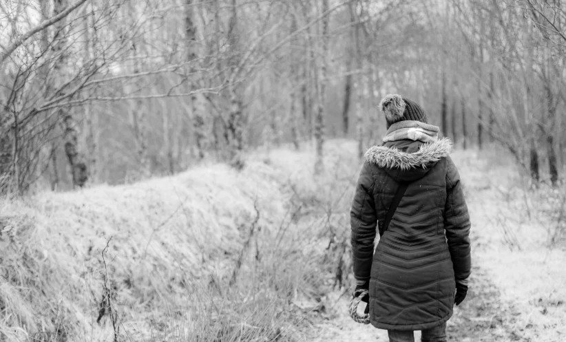 a woman standing in a winter forest wearing a coat