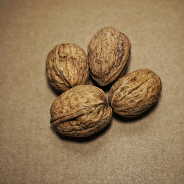 three nuts on a brown surface, with one nut shell still in the shell