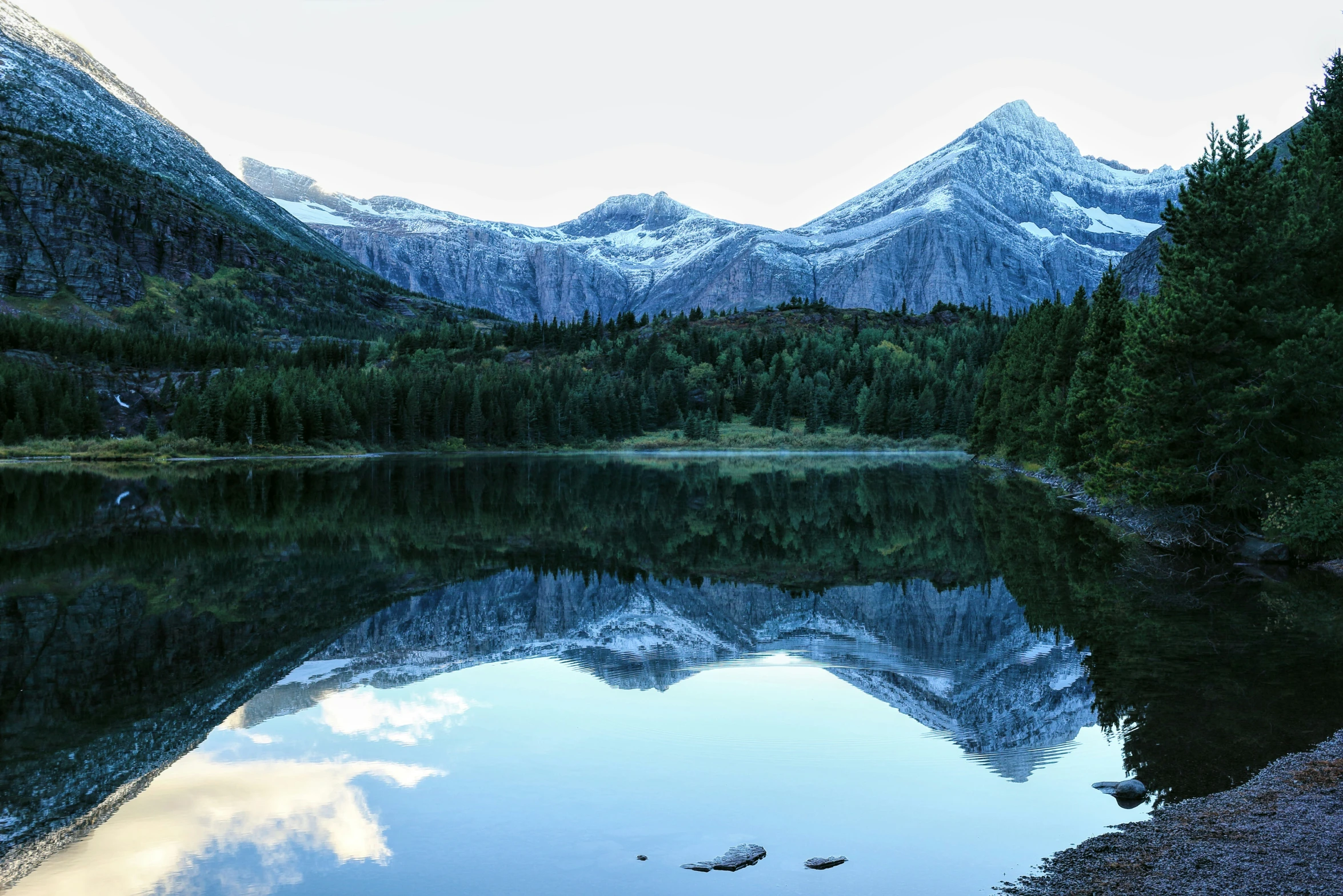 the mountains are shown reflected in a still lake