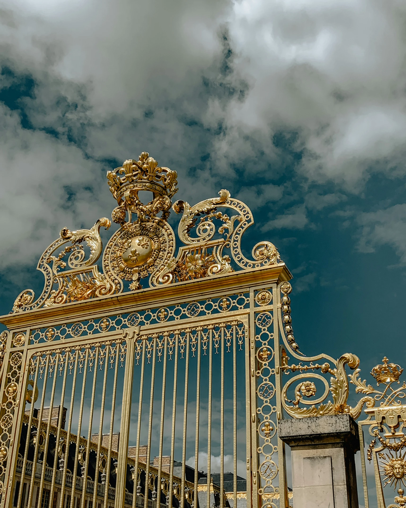the golden gates of an old castle with clouds in the background