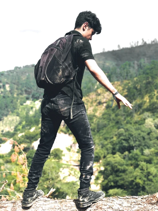 a man looking at the view of some trees with mountains in the background