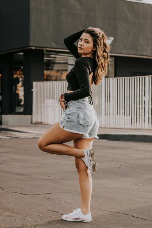 a woman wearing ripped shorts posing in the street