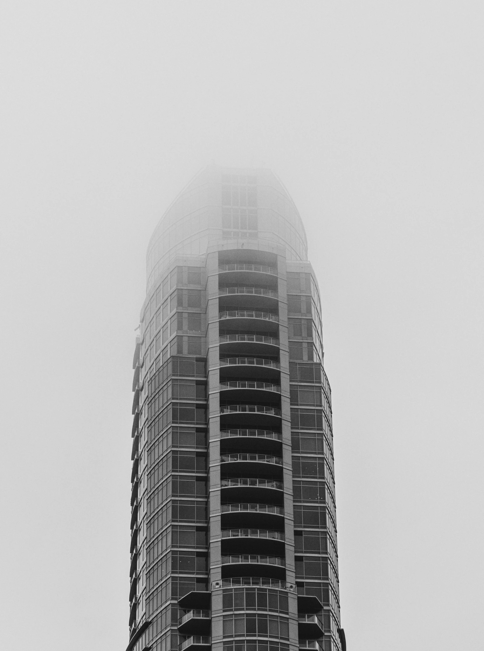 a tall building covered in fog on a cloudy day