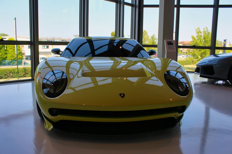 a yellow supercar sitting next to two black cars in a building