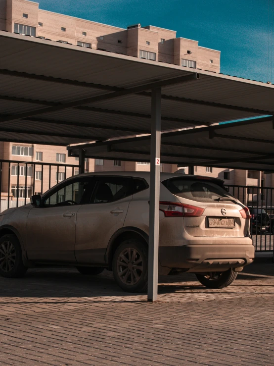 two cars parked under a covered structure on a sidewalk