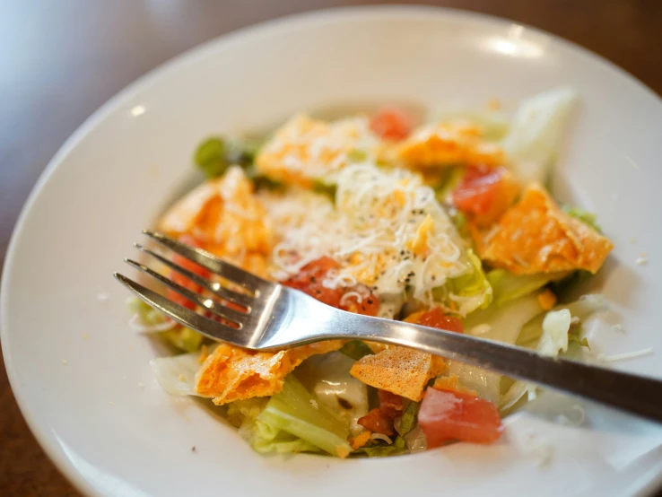 a bowl containing food including salad on it and a fork