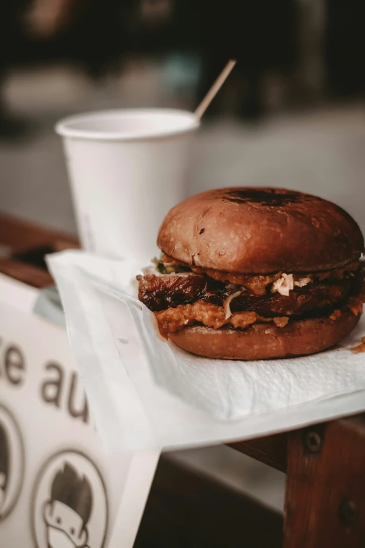 the sandwich is on top of a napkin and has a drink in it