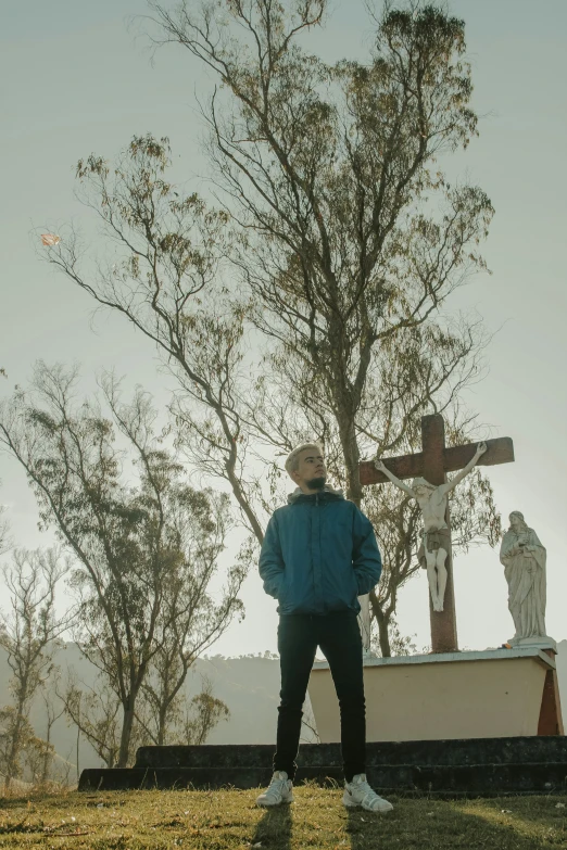 man in blue jacket with cross next to a monument