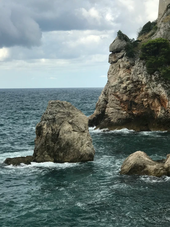 a rocky outcropping is in the ocean by some large rocks