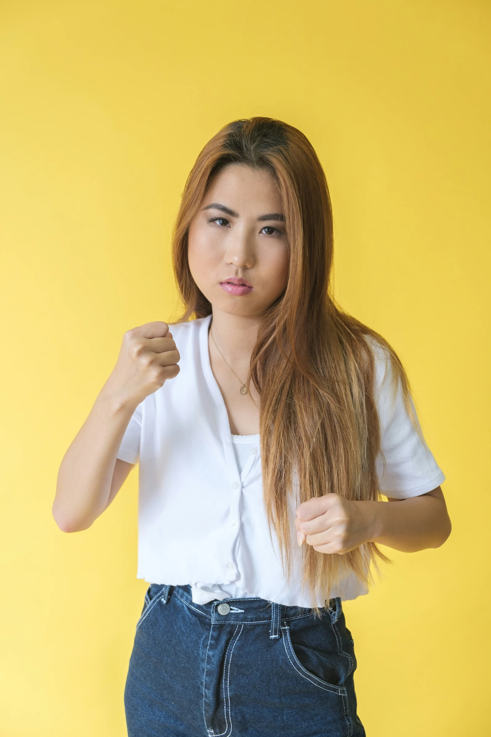 a woman standing in front of a yellow background, making the finger gesture