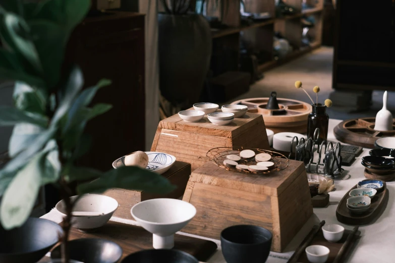 table topped with bowls and vases next to wood stand