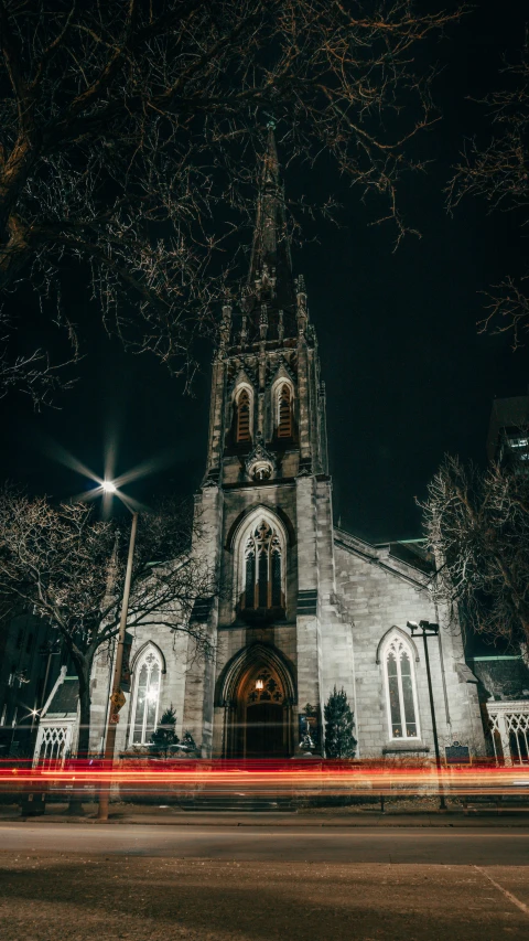 a cathedral with steeple and lit up by headlights