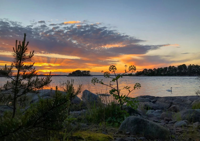 the setting sun at a lake with boats in it