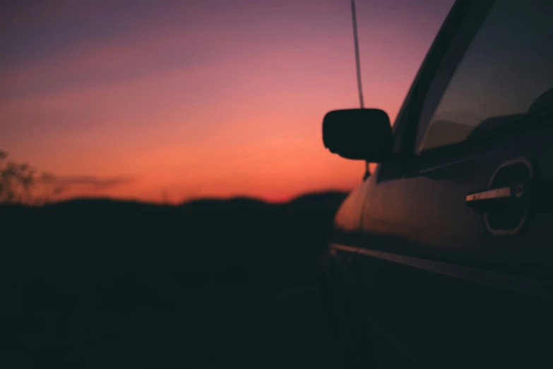 the sun is setting behind the silhouette of a car