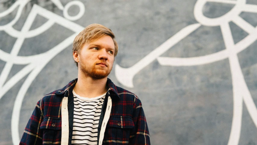 a young man standing in front of a graffitti wall