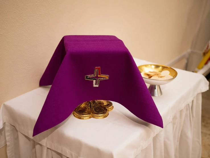 a white table topped with purple cloth and a golden plate