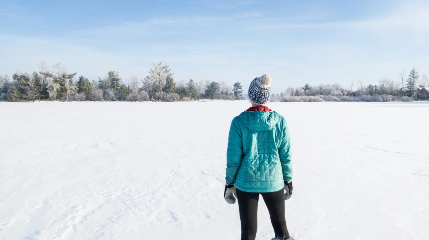 the back view of a woman snowboarding in winter