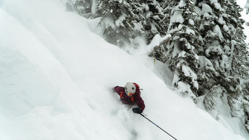 a skier in red shirt going down snowy slope