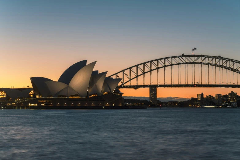 the sydney opera house sits in front of the sydney harbour bridge