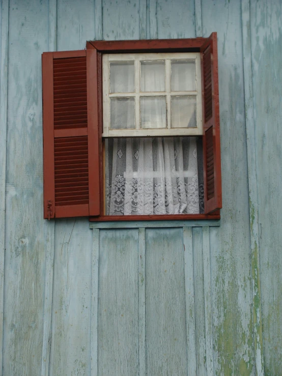 open red shuttered window on wall of old, weathered looking building