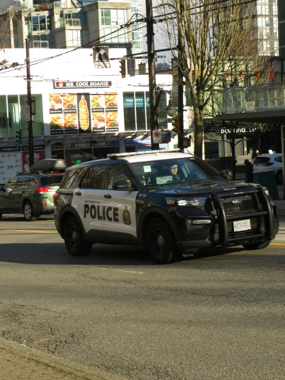 a police car stopped at an intersection with several other vehicles