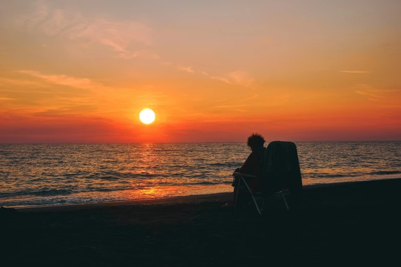 a person sitting on a chair next to a body of water