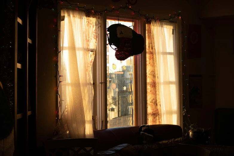 a living room area with sheer curtains and a round wreath hanging from the ceiling