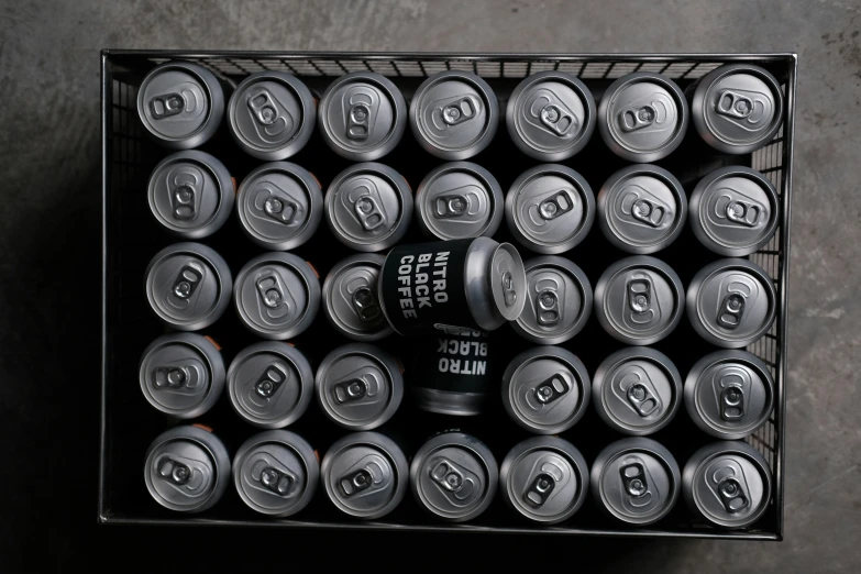 several cans of soda are in an open box