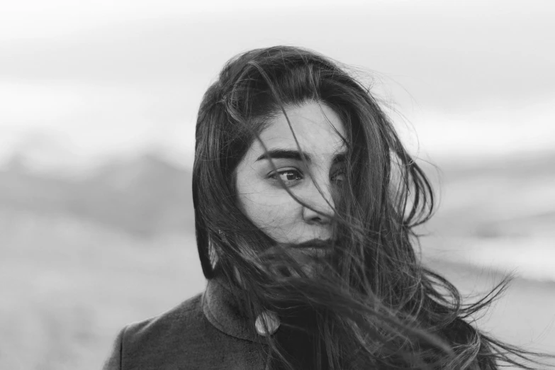 a woman standing in the wind while she has her hair blown