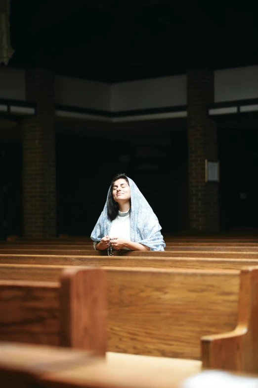 the woman is sitting in the wooden pews