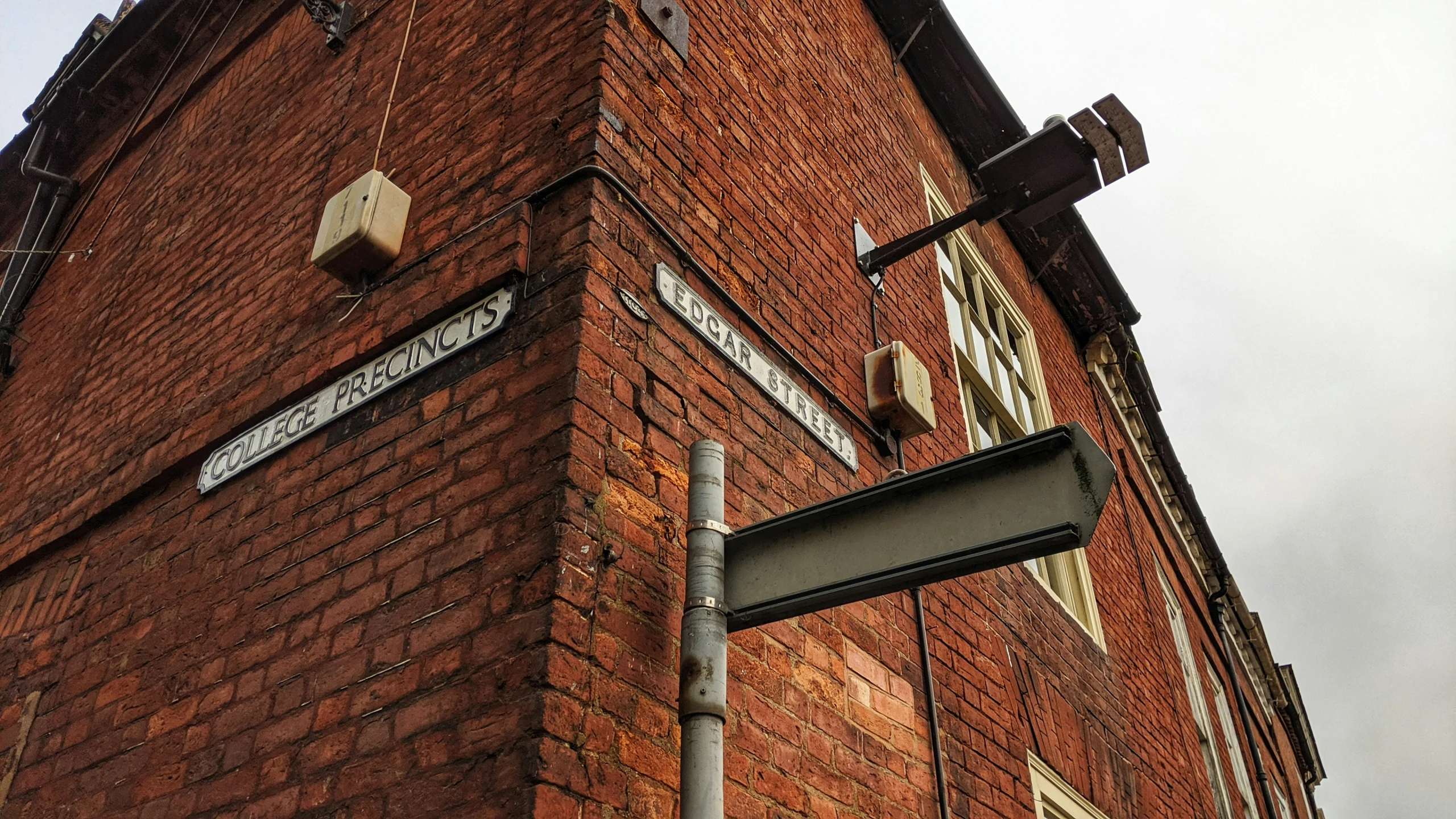 street signs in front of a large red brick building