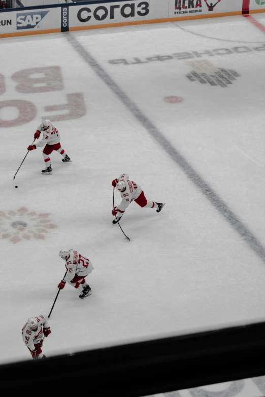 four people in red and white uniforms playing a game on an ice rink