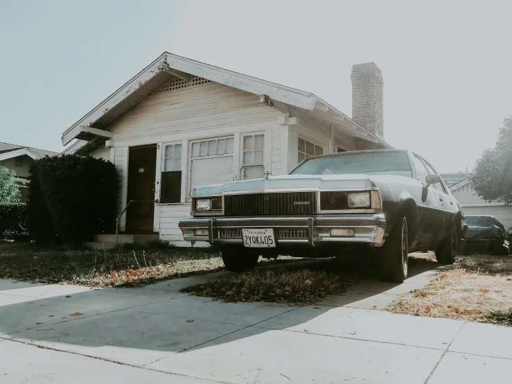 the old car is parked next to a house