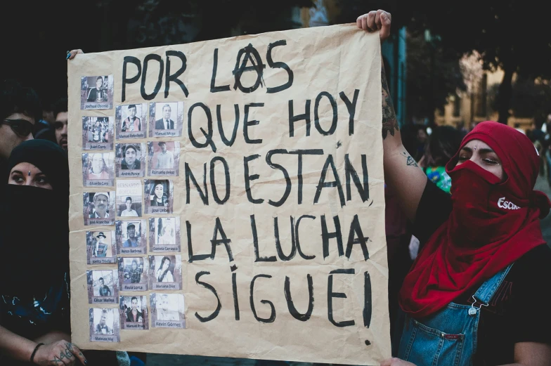 a protester holds a sign in spanish and english