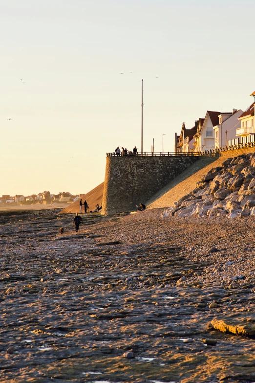 people are walking along the beach at sunset