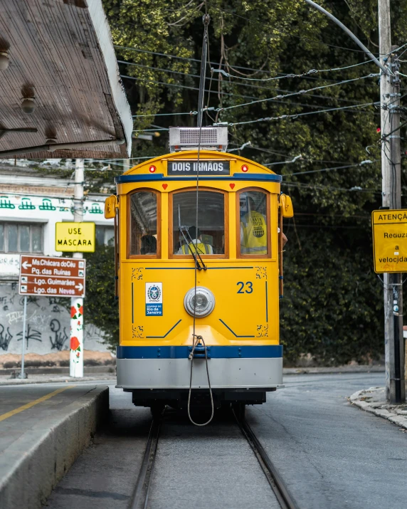 yellow trolley car on track near stop sign