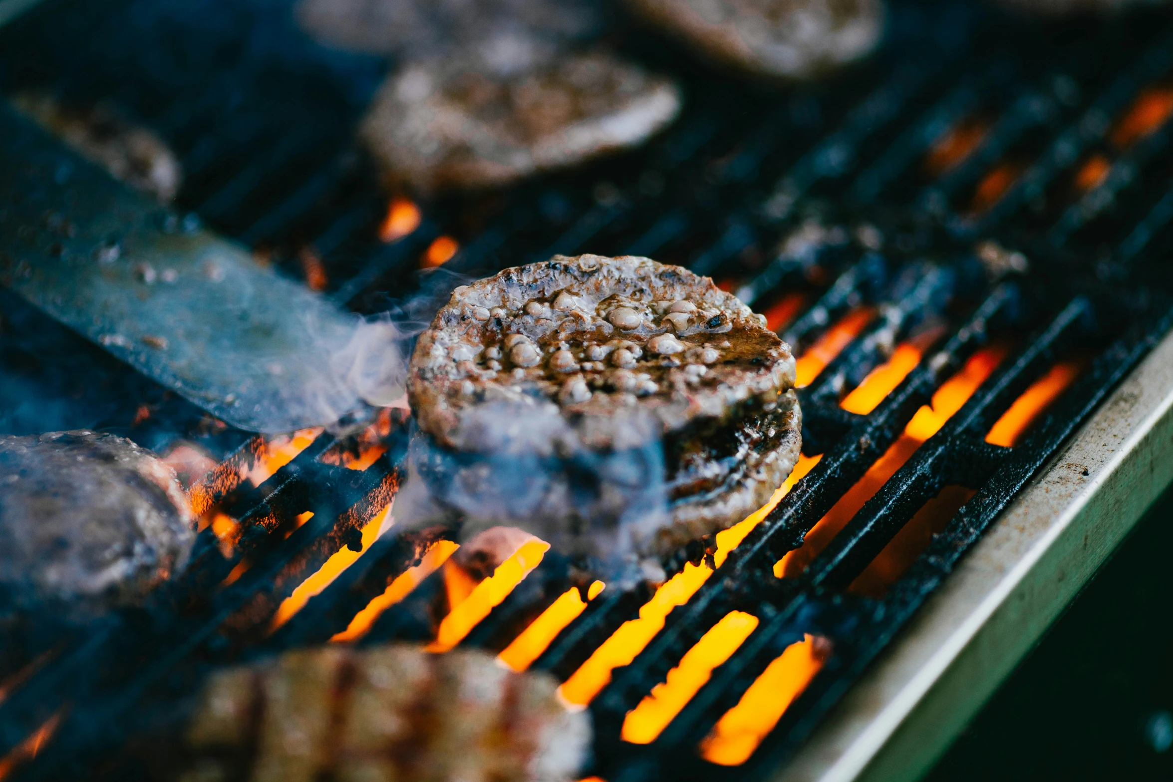 burgers are being cooked on a grill outside