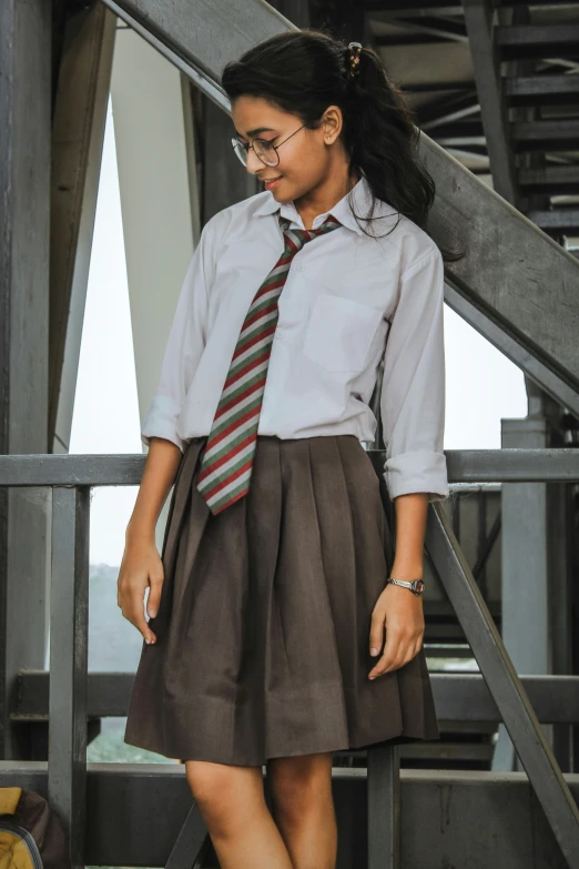 a girl in a white shirt and brown skirt with a striped tie