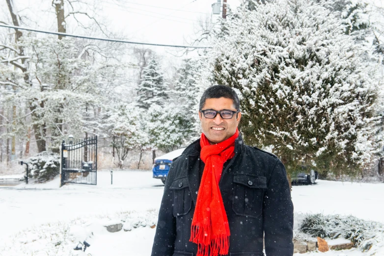 a man standing in the snow wearing a red scarf